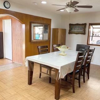 A cozy dining room with a wooden table and chairs, adorned with a ceiling fan and surrounded by windows.