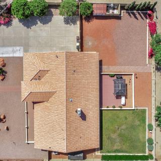 An aerial view of a residential property with a tiled roof, backyard, and driveway.