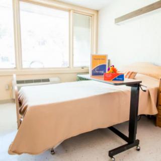 A clean and tidy hospital room with a bed and medical supplies on a tray table.