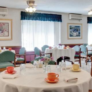 A well-set dining area featuring round tables with colorful cups and neatly arranged chairs.