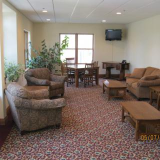 A cozy living room with comfortable seating, a patterned carpet, and a wall-mounted television.