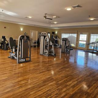 A spacious and well-lit gym area featuring various exercise machines.