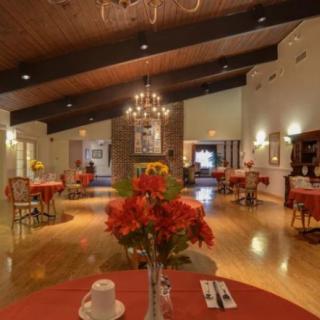A cozy restaurant interior with elegantly set tables and a decorative chandelier.