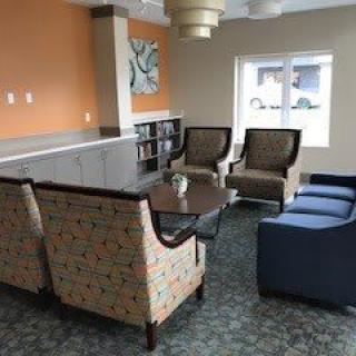 A cozy seating area with various chairs and a central coffee table, set against a warm orange accent wall.