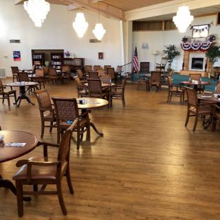 A spacious community center with wooden floors, decorated with tables and chairs.