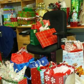 A collection of holiday presents stacked around an office chair.