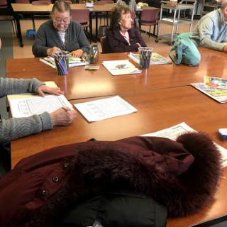 A group of individuals engaged in a meeting around a table, focusing on their work.