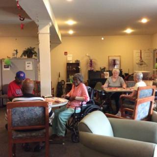 A group of elderly people socializing in a nursing home common area.