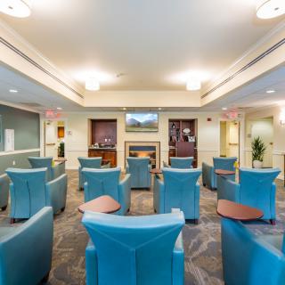 A well-lit waiting room with arranged seating and a central television.