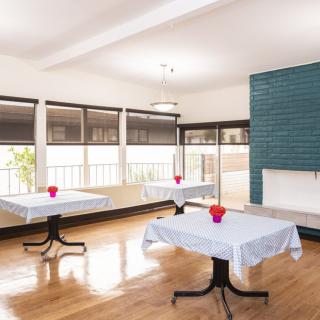 A modern dining area with tables set for guests, featuring white tablecloths and floral centerpieces.