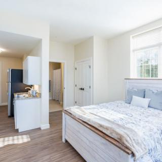 A bright and minimalist bedroom with wood flooring and natural light.
