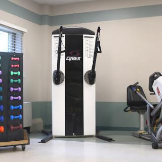 A well-equipped gym area featuring a cable machine and various weights.
