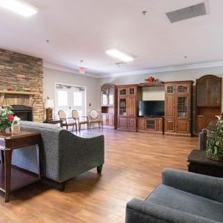 A spacious living room with wooden flooring, featuring a comfortable seating area, a television, and a fireplace.