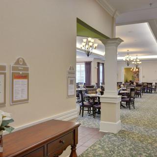 A spacious dining room with elegant furniture and chandeliers.