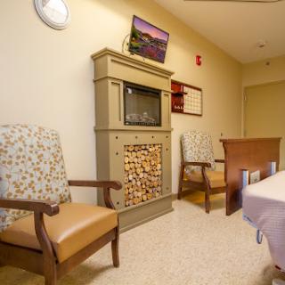A cozy waiting area featuring comfortable chairs, a decorative fireplace, and a television.