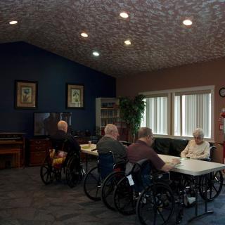 A group of seniors in wheelchairs gathered in a community room at a nursing home.