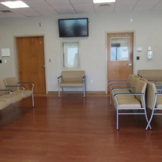An empty waiting room with chairs and a television on the wall.