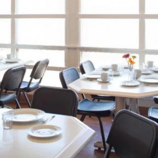An empty dining area with neatly set tables and chairs by large windows.
