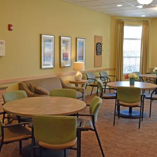 A cozy lounge area with tables and chairs arranged for seating, featuring warm lighting and wall decorations.
