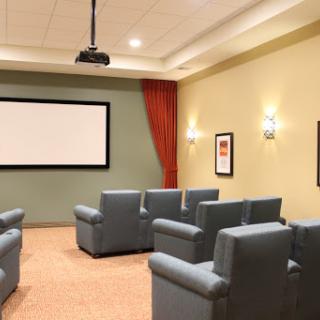 A cozy home theater setup featuring comfortable recliner seating and a projector screen.