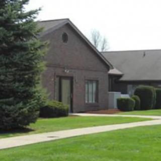 A suburban house with a well-maintained lawn and surrounding trees.