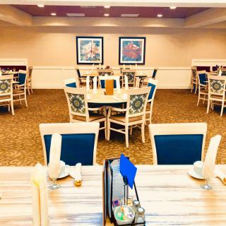 A well-lit dining area with neatly arranged tables and chairs, featuring elegant decor.