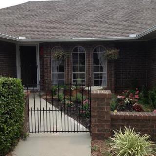 A cozy brick house with a small garden and a gated front yard.