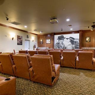 A cozy home theater featuring rows of recliner chairs and a large projector screen.