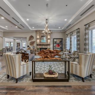 A luxurious living room featuring elegant furniture, a central chandelier, and large windows.