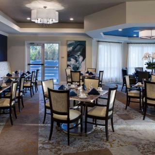 An elegant dining room with neatly arranged tables and chairs, featuring a modern chandelier.
