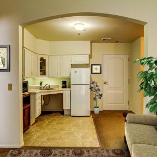 A cozy apartment kitchen with a comfortable living area, featuring a fridge and sofa.