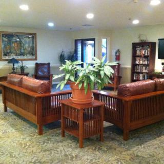 A cozy living room with wooden furniture and a central plant.