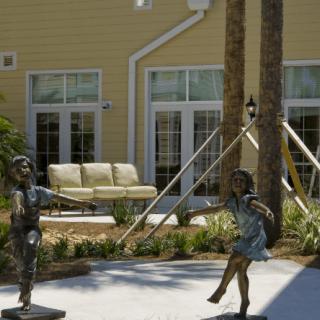 Bronze sculptures of children playing in a garden setting.