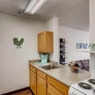 A small kitchen area featuring wooden cabinets, a countertop with a sink, and decorative wall art.