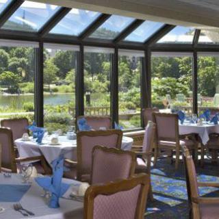 A restaurant dining area with tables and chairs, offering a scenic view through large windows.