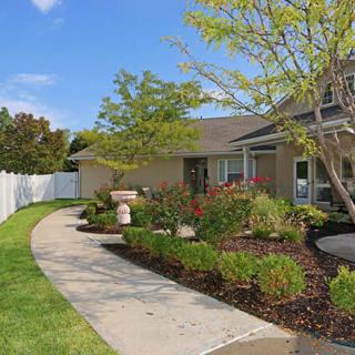 A well-maintained garden with a winding pathway leading to a charming house.