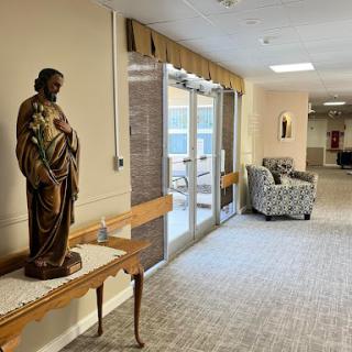 A well-lit hallway featuring a decorative statue and comfortable seating.