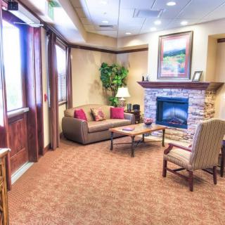 A cozy living room featuring a comfortable seating area with a sofa and armchair, complete with a fireplace and decorative elements.
