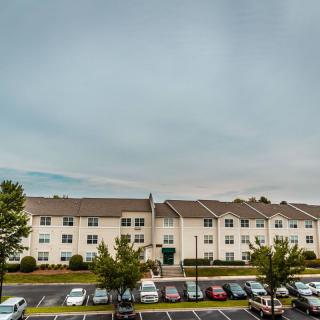 A residential building with a parking lot full of cars and overcast sky.