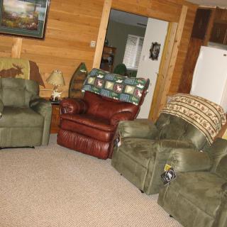 A cozy living room with comfortable chairs and wood paneling.