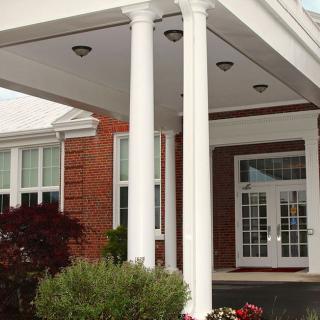 A building entrance with white columns and brick exterior.