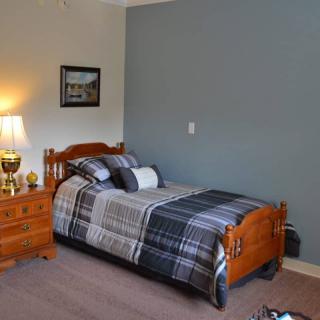 A cozy bedroom features a single wooden bed with patterned bedding, accompanied by a nightstand and lamp, set against a two-toned wall.