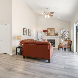 A cozy living room featuring a sofa set and armchair, with a fireplace as the focal point, decorated in warm tones and complemented by wood flooring.