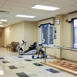 A rehabilitation room equipped with exercise machines and parallel bars for physical therapy.