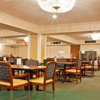 A spacious dining area with neatly arranged tables and chairs, illuminated by a chandelier.