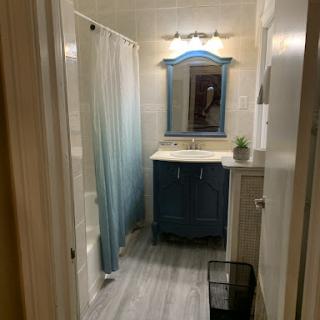 A modern bathroom featuring a sink with a blue cabinet, a mirror, and a shower area.