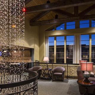 A cozy interior with a chandelier, comfortable seating, and large windows offering a view.
