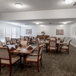 An elegantly furnished dining room with multiple tables and chairs, set in a well-lit interior space.