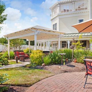 A scenic garden patio with outdoor seating and lush greenery surrounding a charming building.