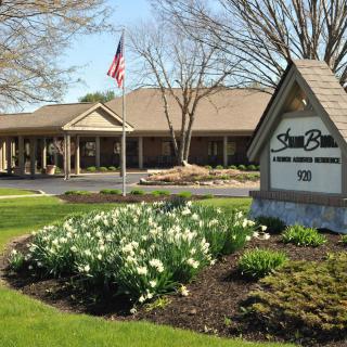 A building with landscaped gardens, featuring a sign and an American flag.